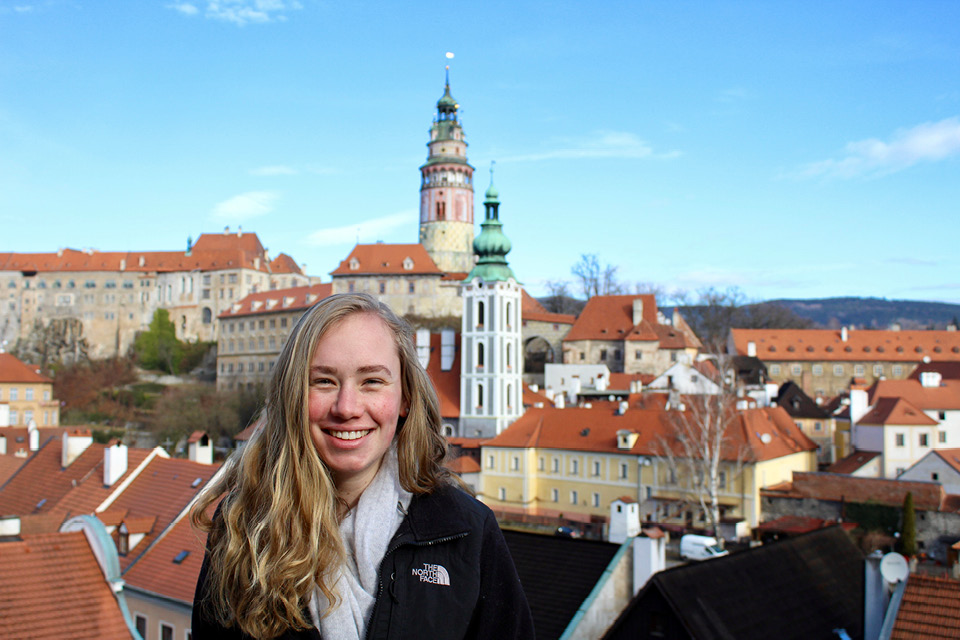 Izzy standing in front of a view of building in Prague