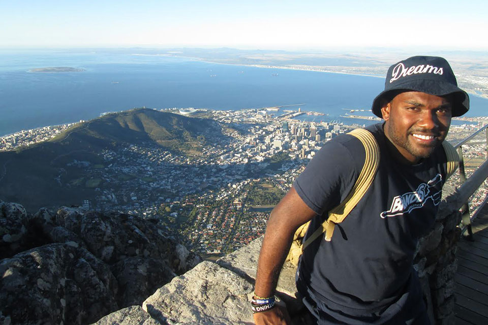 Joel Burt-Miller standing in front of an aerial view of Cape Town, South Africa
