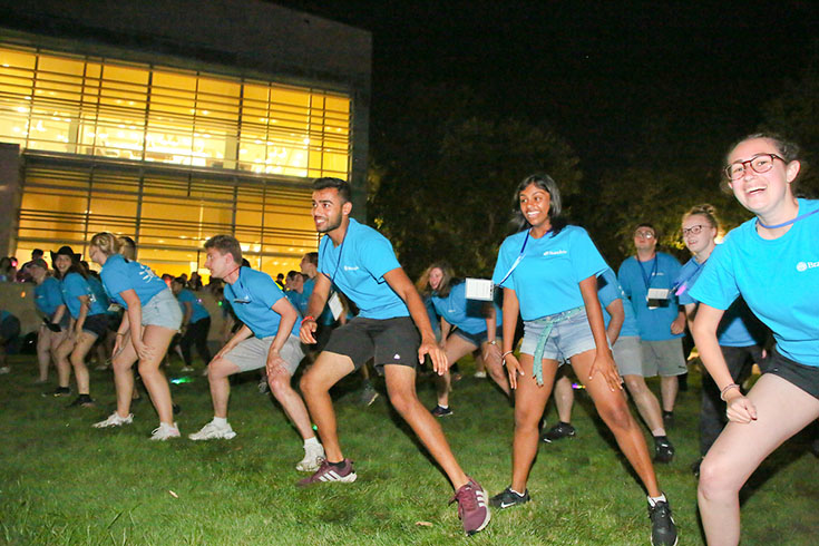 group of students in blue shirts dancing outside at night