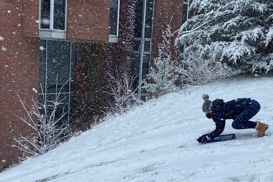 Person sledding down a hill on campus