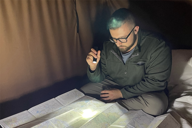 Van looking over his map with a flashlight