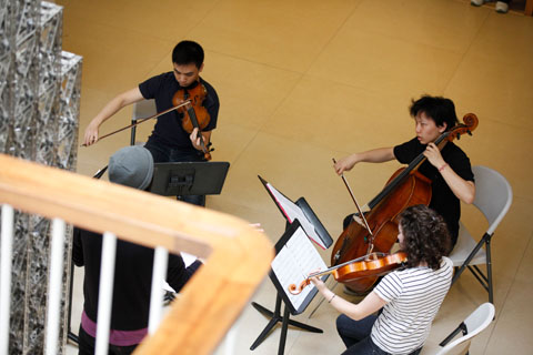 A musical performance including two violinists and a cellist, photographed from above.