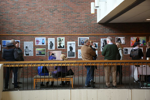 Attendees milling about, chatting and viewing images posted on the wall.