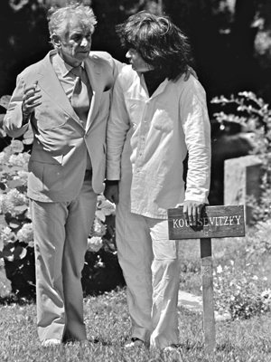 Leonard Bernstein with arm around Seiji Ozawa, while Ozawa leans on the grave marker of Koussevitzky