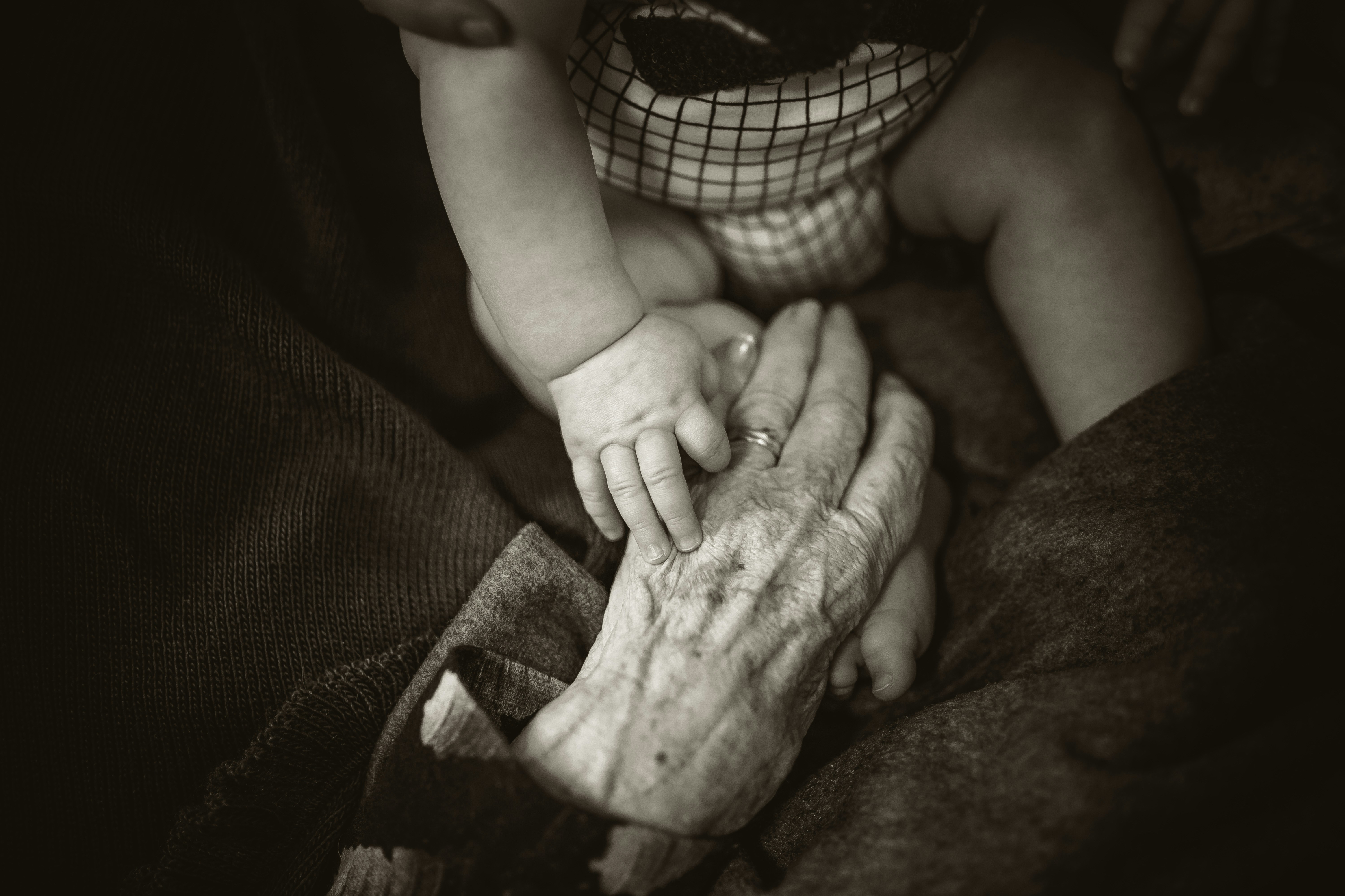 A baby touches a wrinkled hand