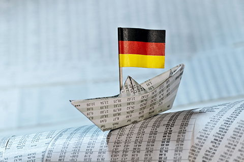 Paper boat with a german flag floating in a paper sea