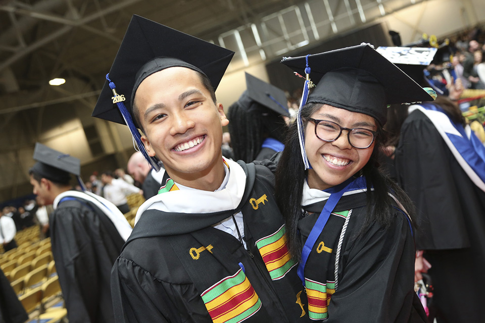 Two graduates hug, as newly-minted alumni!