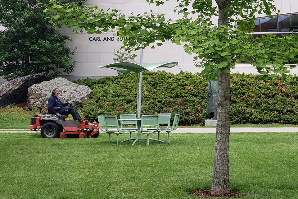 Facilities staff at work: Man mowing the lawns.