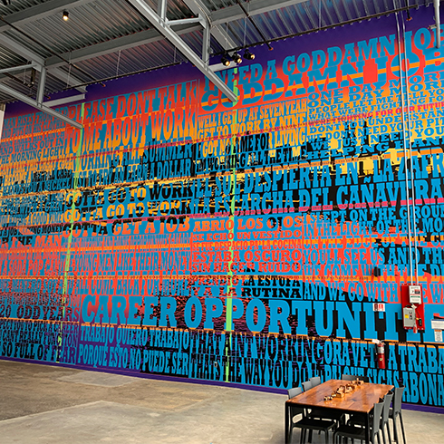 large mural by Joe Wardwell which is brightly colored with words printed on top of a city scape