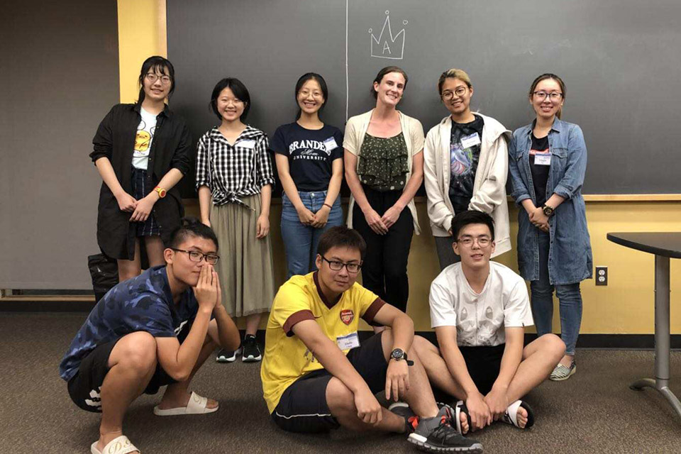 students and faculty member pose in front of classroom chalkboard