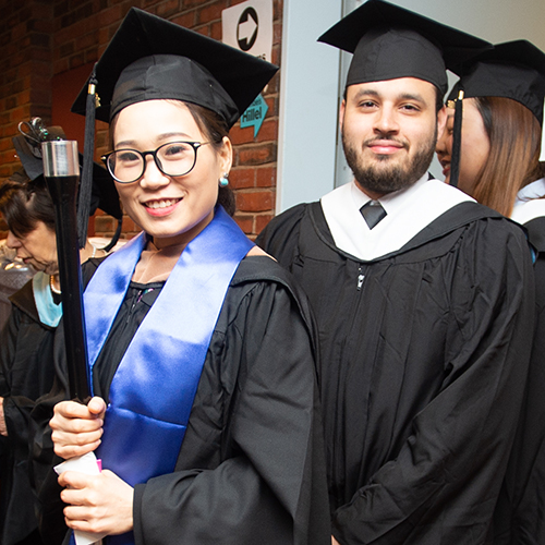 female and male students walking into graduation ceremony in cap and gown