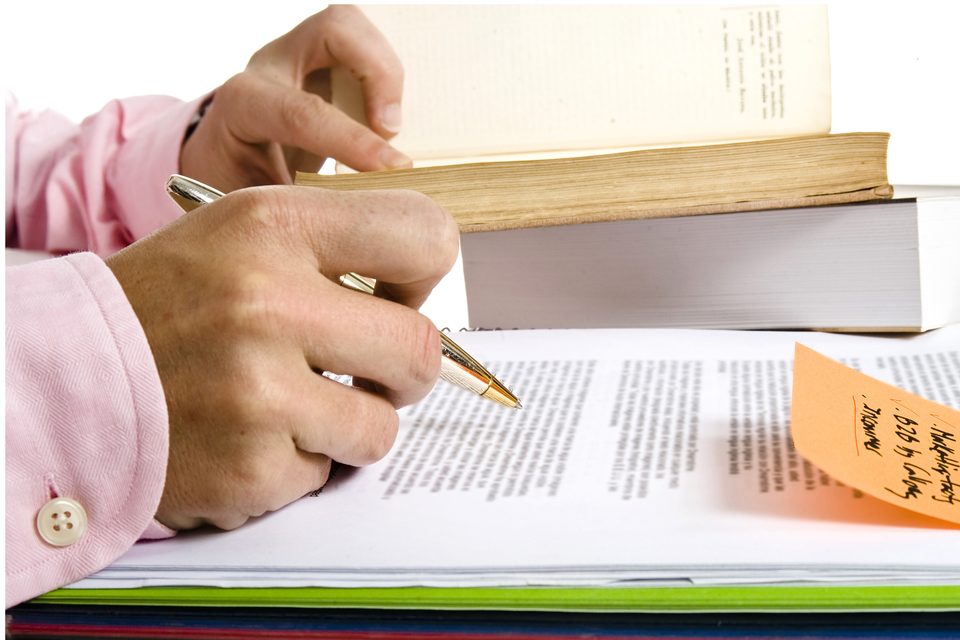 Mans hand signing papers involving patents, copyrights, and trademarks