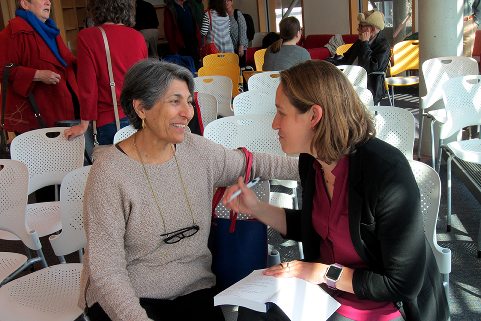 Two women, seated, in an animated conversation