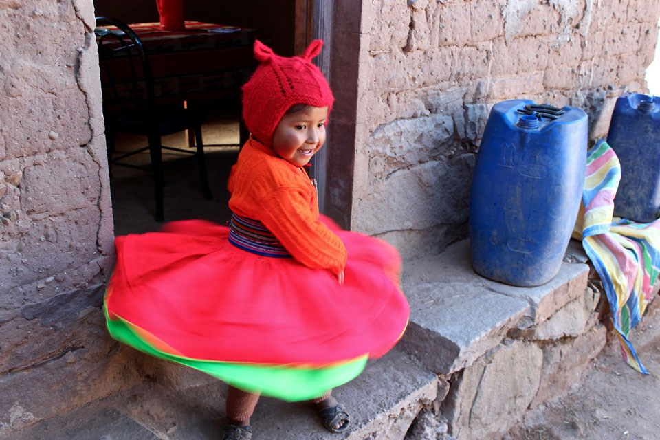 Little girl with knit hat and colorful clothes twirling around.