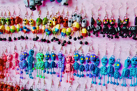 Colorful skull or calaverita earrings hanging on a display.