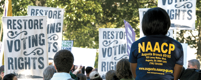 Photo of a protest showing people with "Restore voting rights" placards