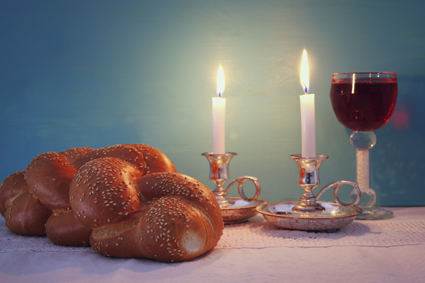 Challa, lit candles and wine on a table for Shabbat