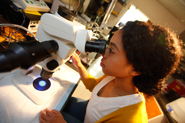 A young woman looking into a microscope