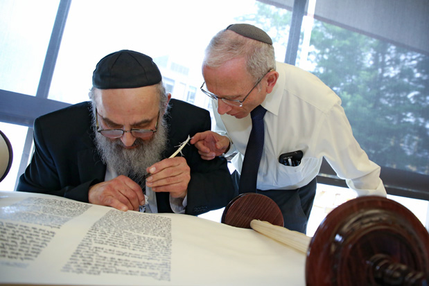 University professor Jonathan Sarna touches a quill being used by Rabbi Binyomin Spiro to finish a Torah scroll