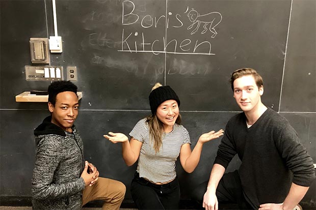 3 people crouch in front of a blackboard that says "Boris' Kitchen".