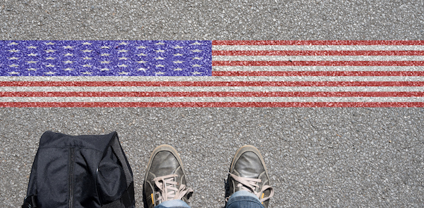 Feet near a line painted as an American flag on asphalt