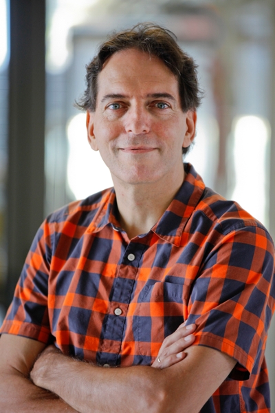 Jeff Gelles, professor of Biochemistry and Molecular Pharmacology, in a plaid shirt with arms folded