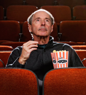 American studies professor Thomas Doherty seated in a theater eating popcorn