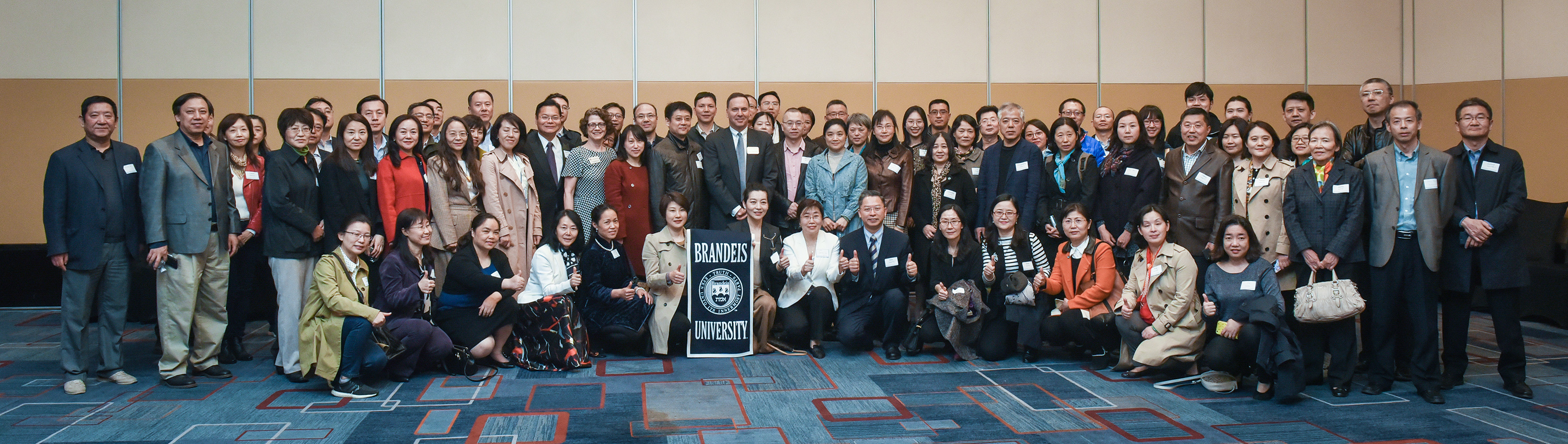 President Ron Liebowitz standing behind a Brandeis banner with several dozen parents of students in China