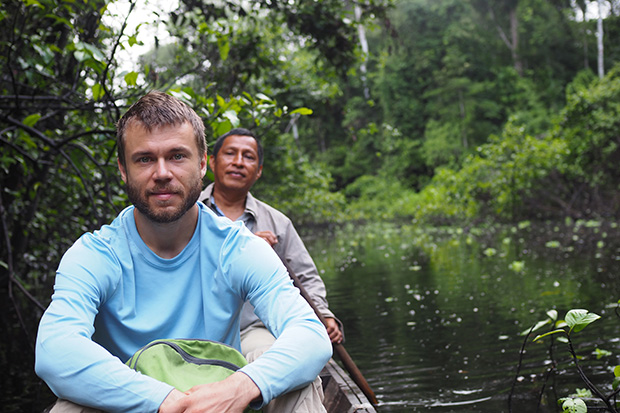 John Wilmes inside a canoe on a river in the Amazon rainforest