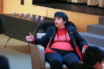 Inge Auerbacher, who survived the Terezin concentration camp as a child, seated in a chair with in a red shirt and black blazer