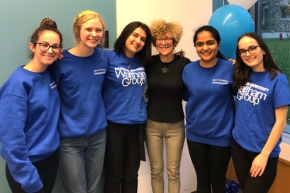 female students in blue Waltham Group t-shirts stand with arms around each other