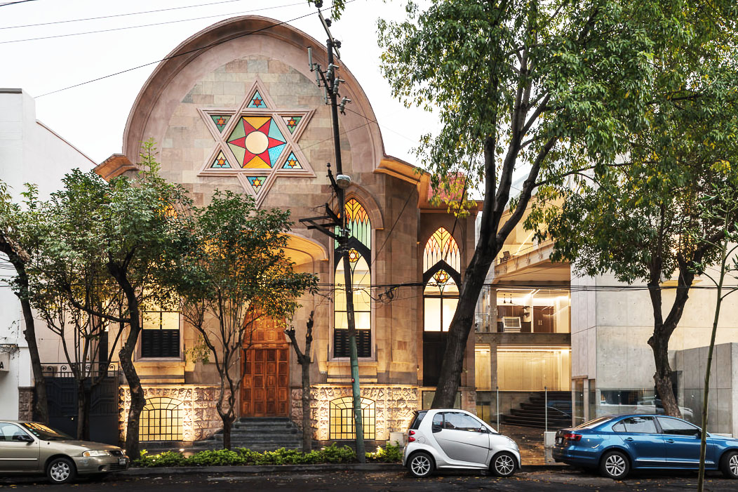 the exterior of the Rodfe Sedek synagogue in Mexico, with an arched stone front with a large stained glass star of David on the facade