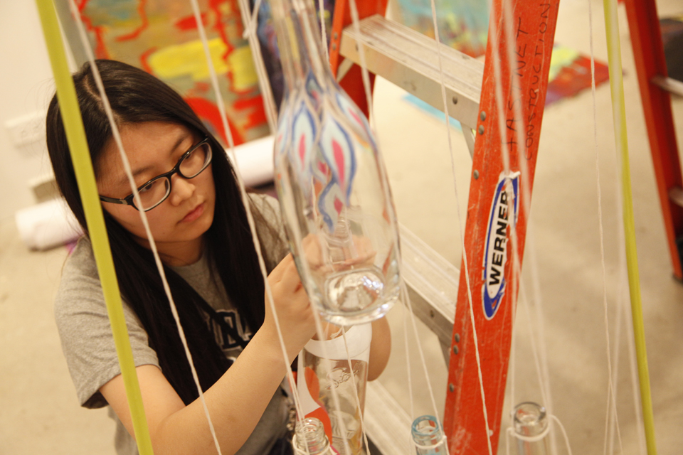 Female student installing glass art piece