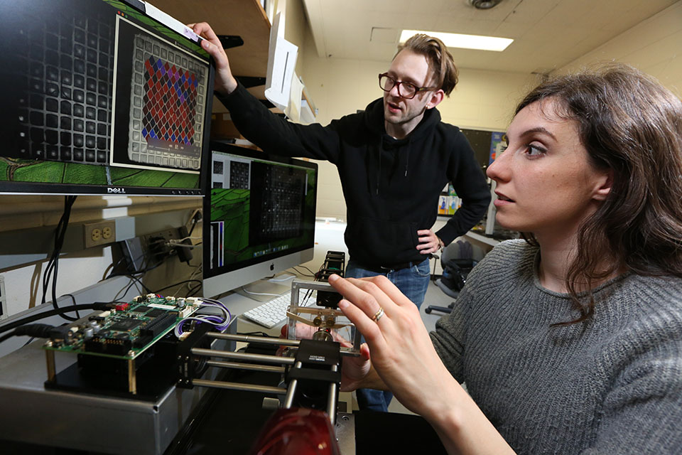Two students in a physics lab looking at a computer