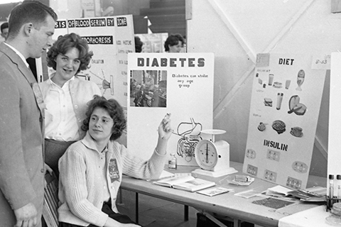 Woman sits at science show and discusses her diabetes research