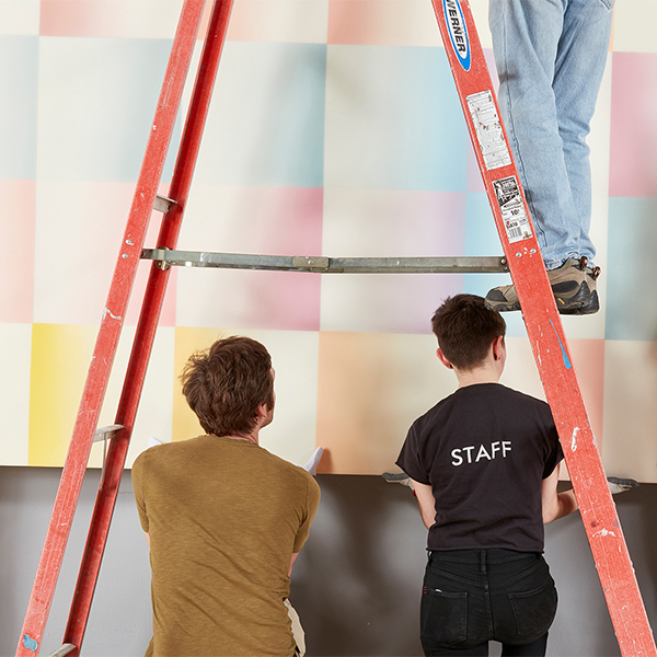 Rose Art Museum staff hang a painting on the wall