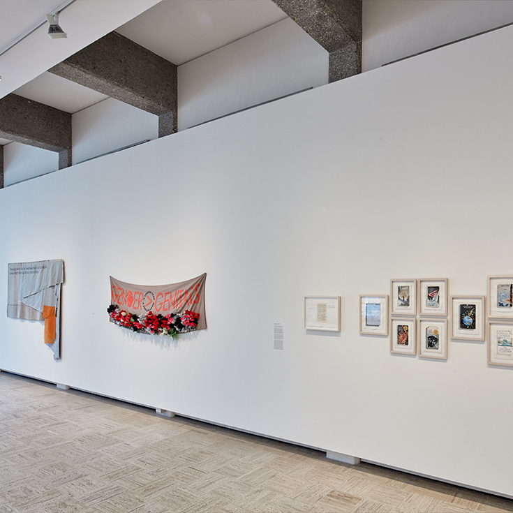 Installation shot of Tuesday Smillie exhibition at the Rose art museums featuring two protest banners and watercolor interpretations of book covers 