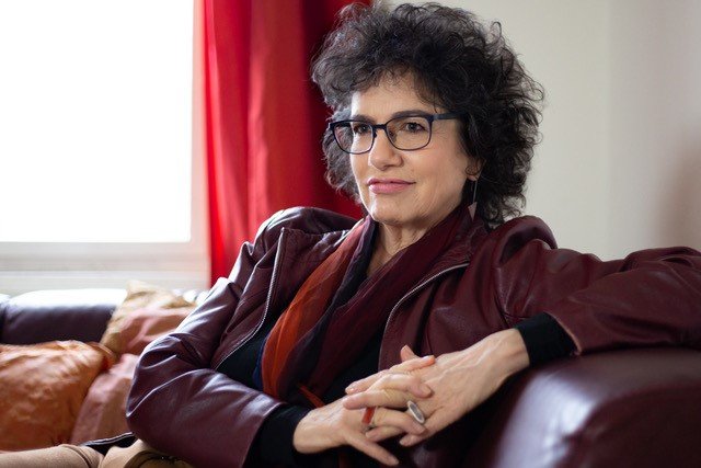 Susan Neiman seated on a leather sofa with her hands folded 