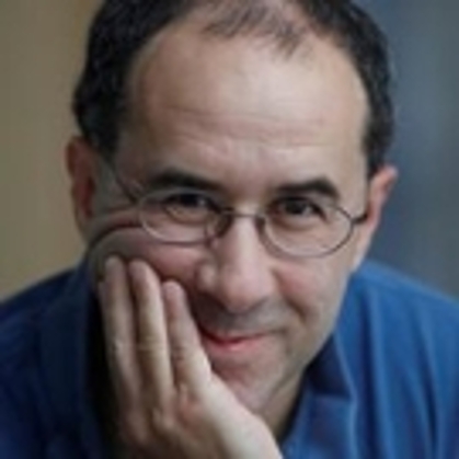 Michael Rosenthal wearing a blue shirt and glasses, smiling with his head in his hand 