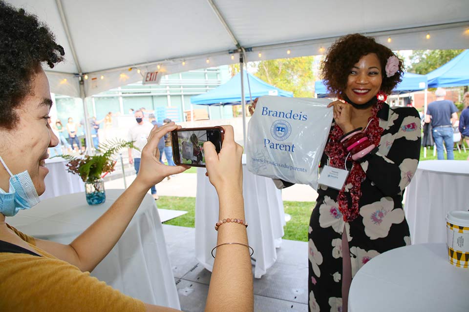 Person smiling holding a bag that reads "Brandeis Parent"