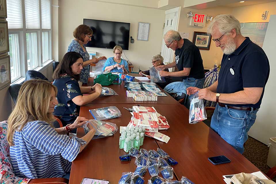 A group of volunteers sits around a table, organizing items in plastic bags