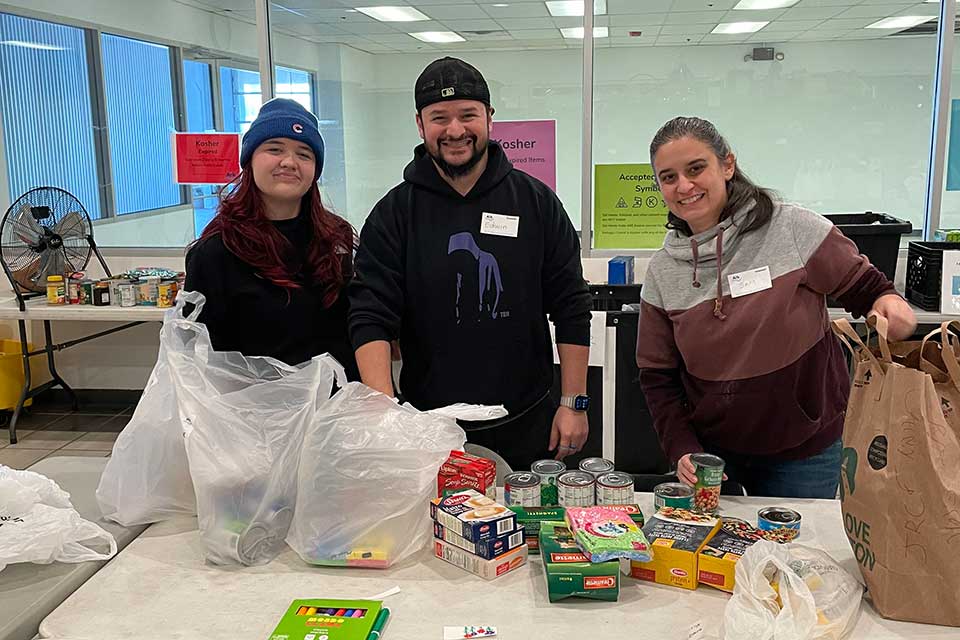 Three volunteers smile while organizing food at The Ark.