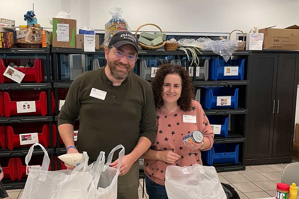 Two volunteers smile while stocking and organizing food at The Ark.