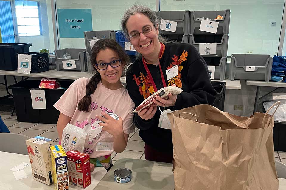 A woman and child smile and organize food at The Ark.