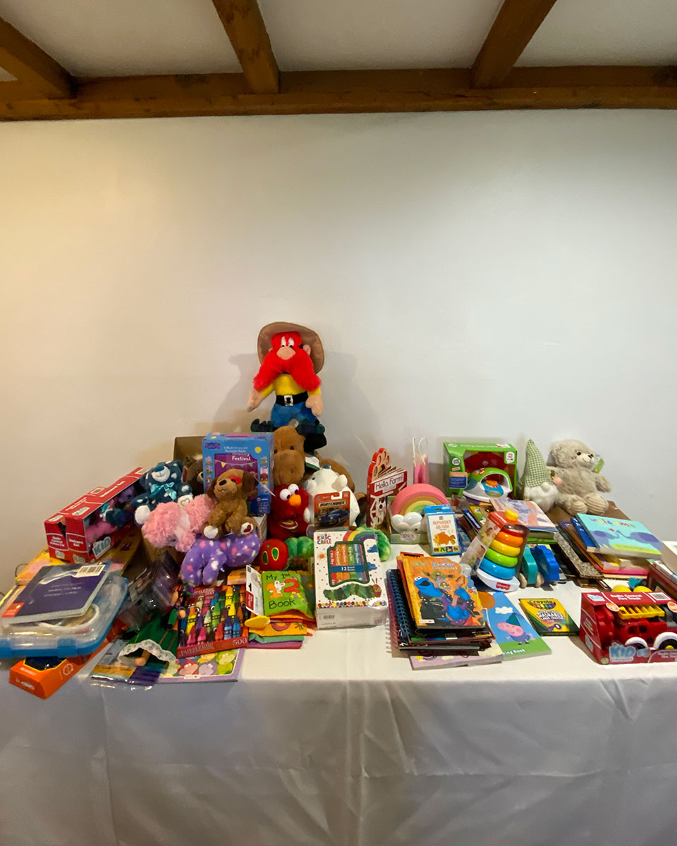 A table topped with a pile of children's books and toys to be donated.