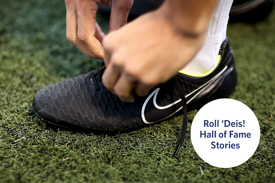 Hands tying a cleat on a soccer field. 