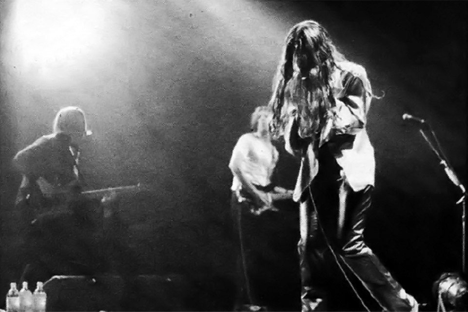 Alanis Morrisette performing on stage with a band with hair covering her face.