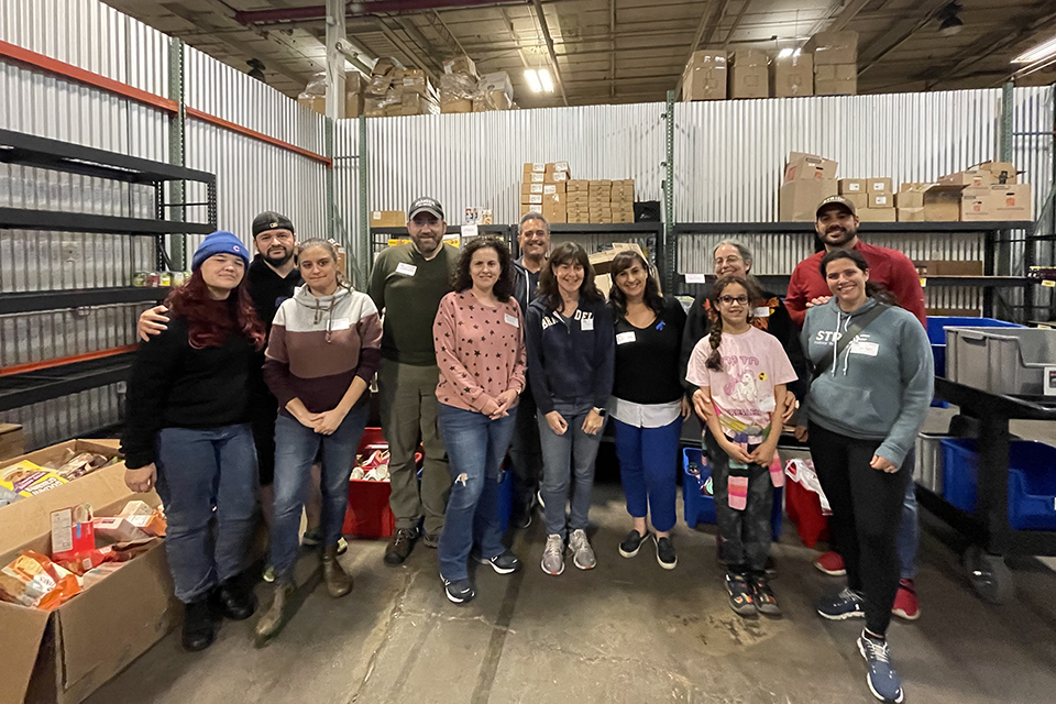 Alumni and friends pose in the stock room of a food pantry.