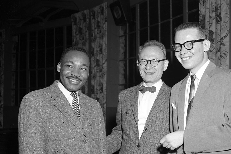 Martin Luther King Jr. smiles with two other people on his visit to Brandeis University