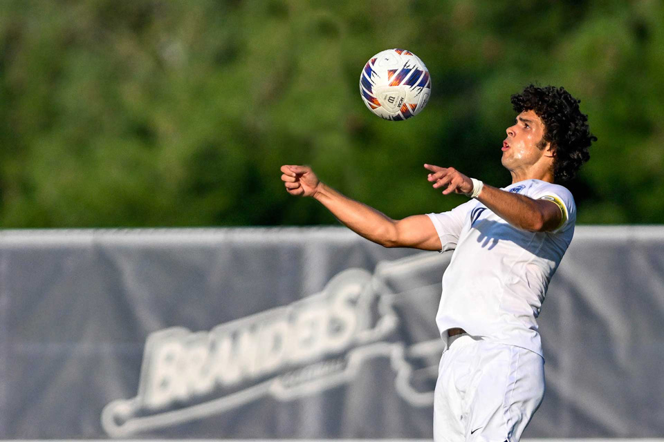 A student heads a soccer ball while jumping in the air 